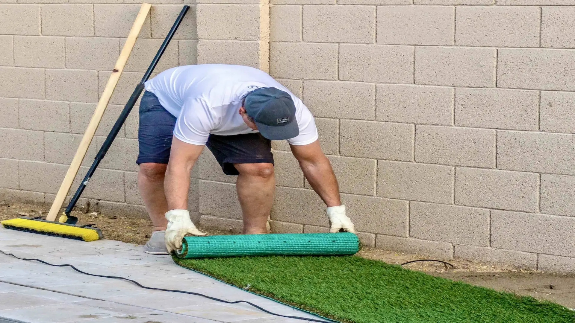 adult male rolling out installing artificial grass turf